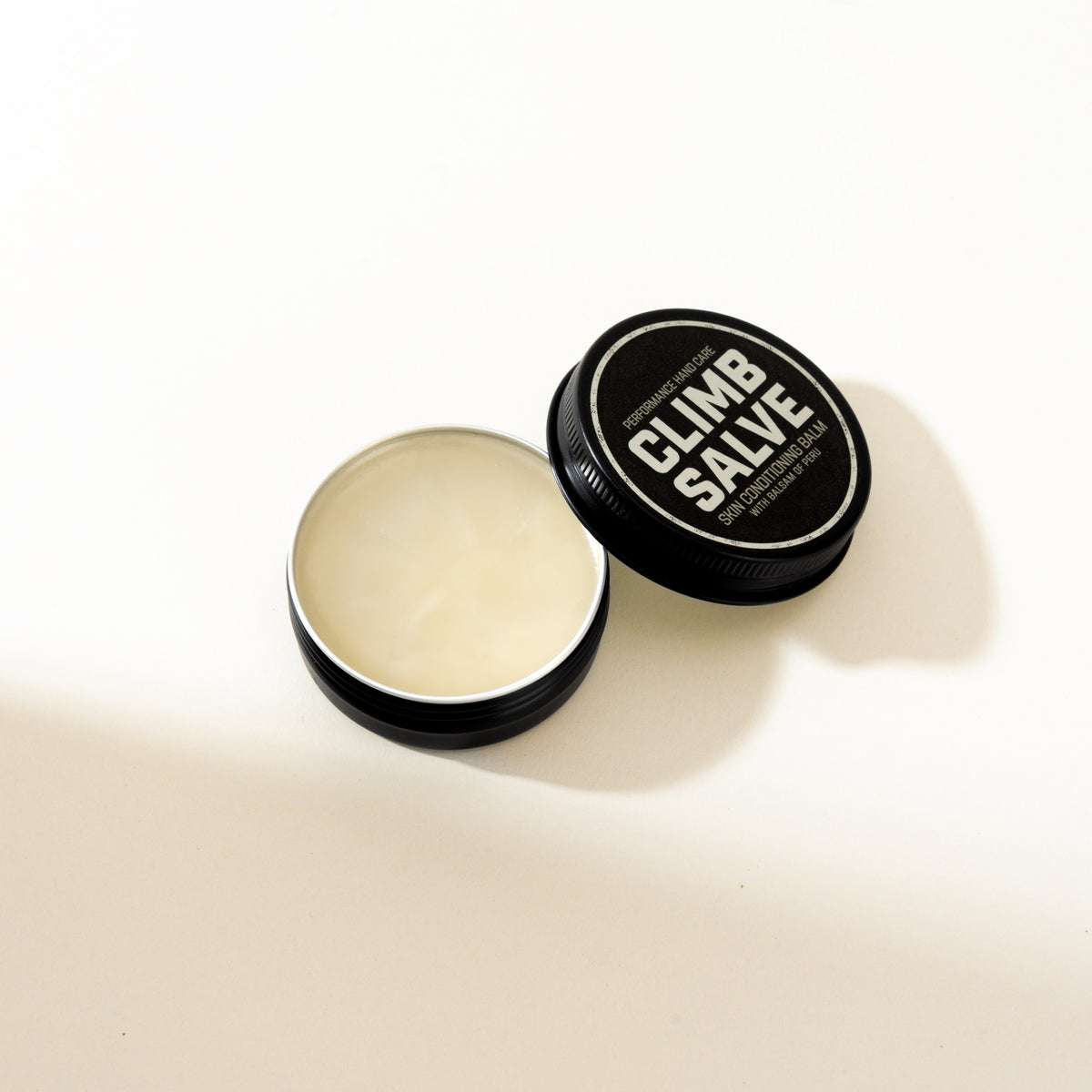 Climb Salve open balm with lid leaning beside the tin