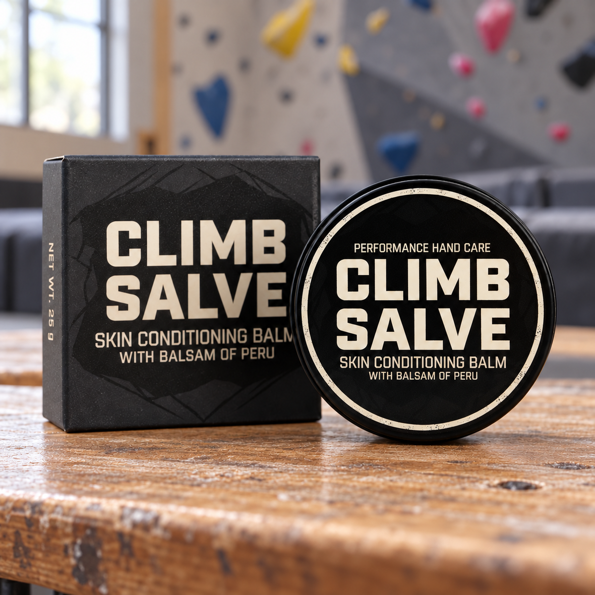 Climb Salve 25g tin and dark retail box on a bench in a climbing gym