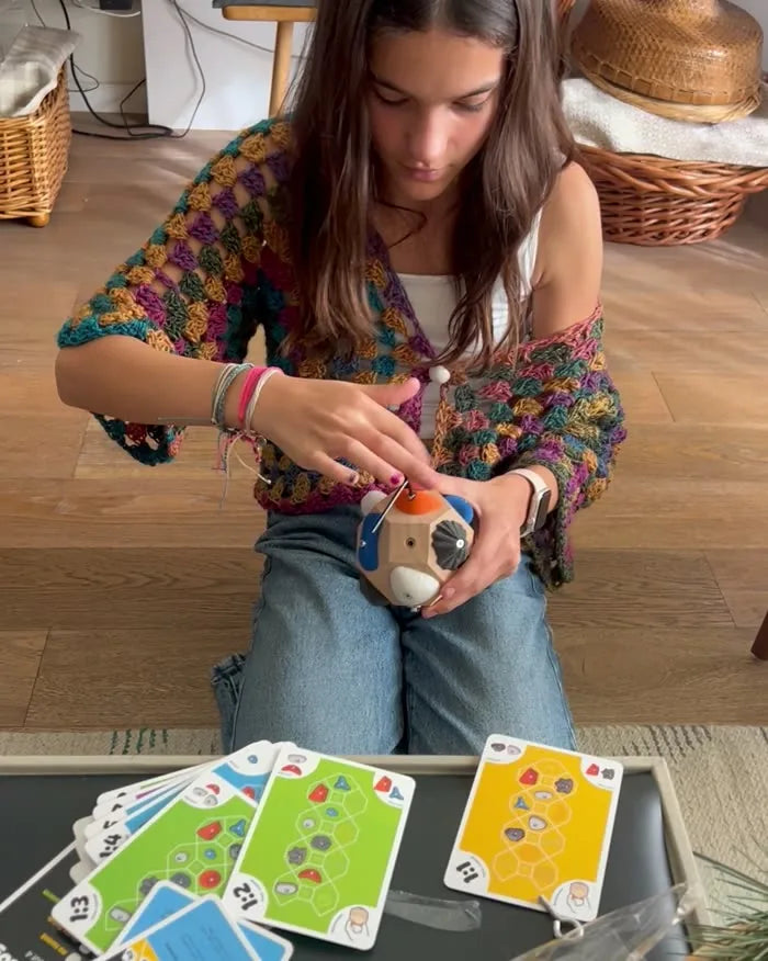 A teenage girl working a route on the Boulder Block, route cards spread on the table in front of her
