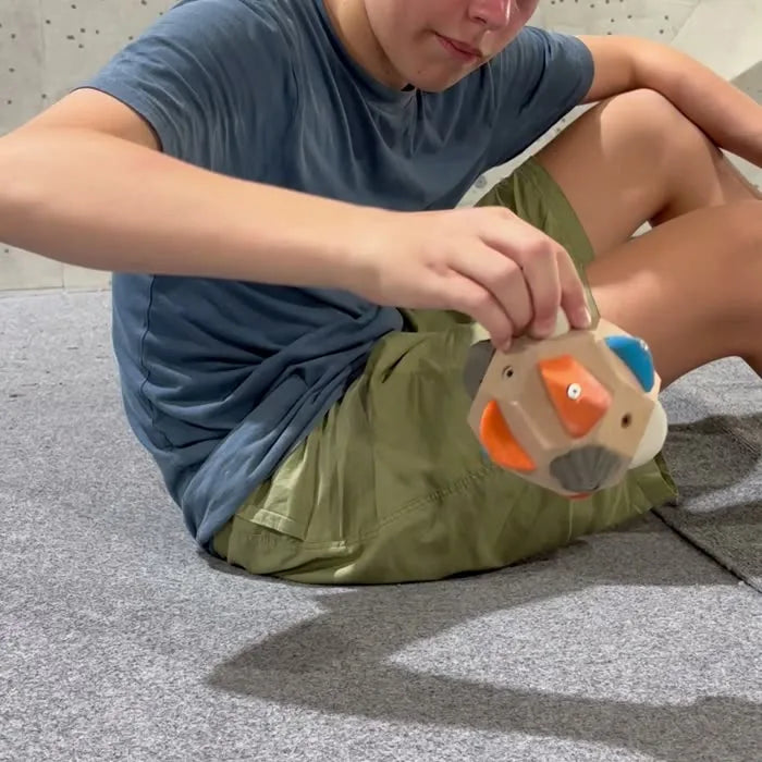 A teenager working a route on the Boulder Block with his fingers