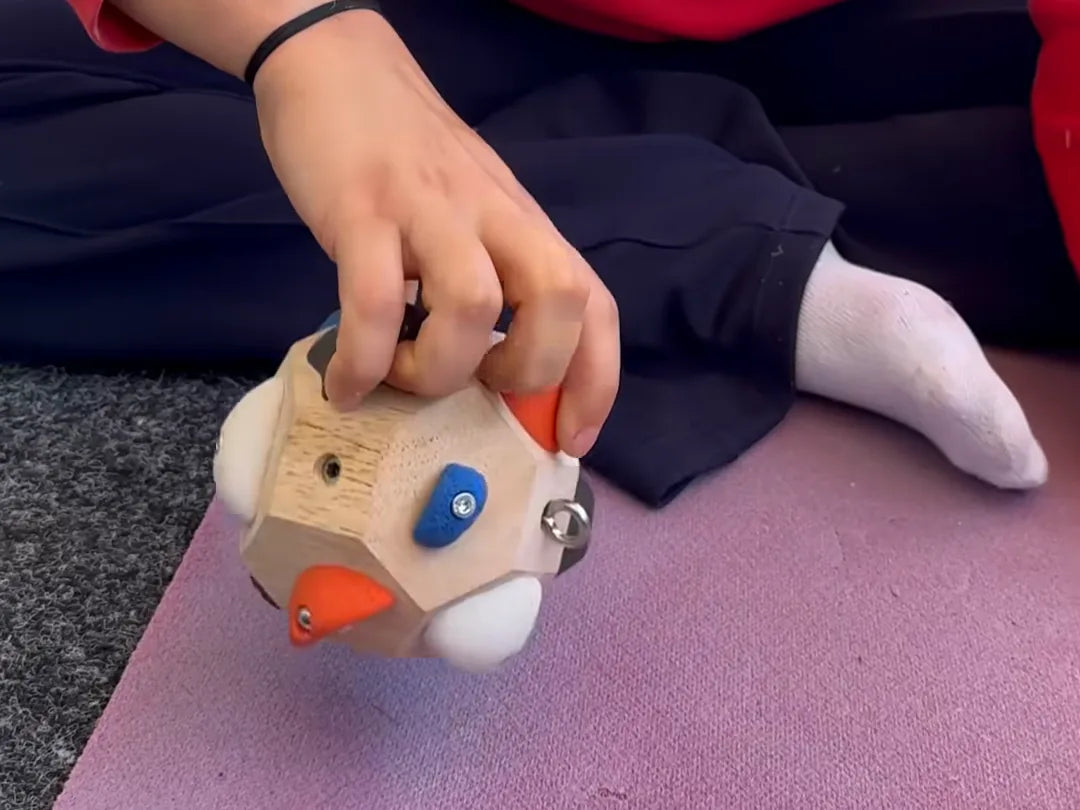 A child's hand on the Boulder Block, fingers on two of its climbing holds